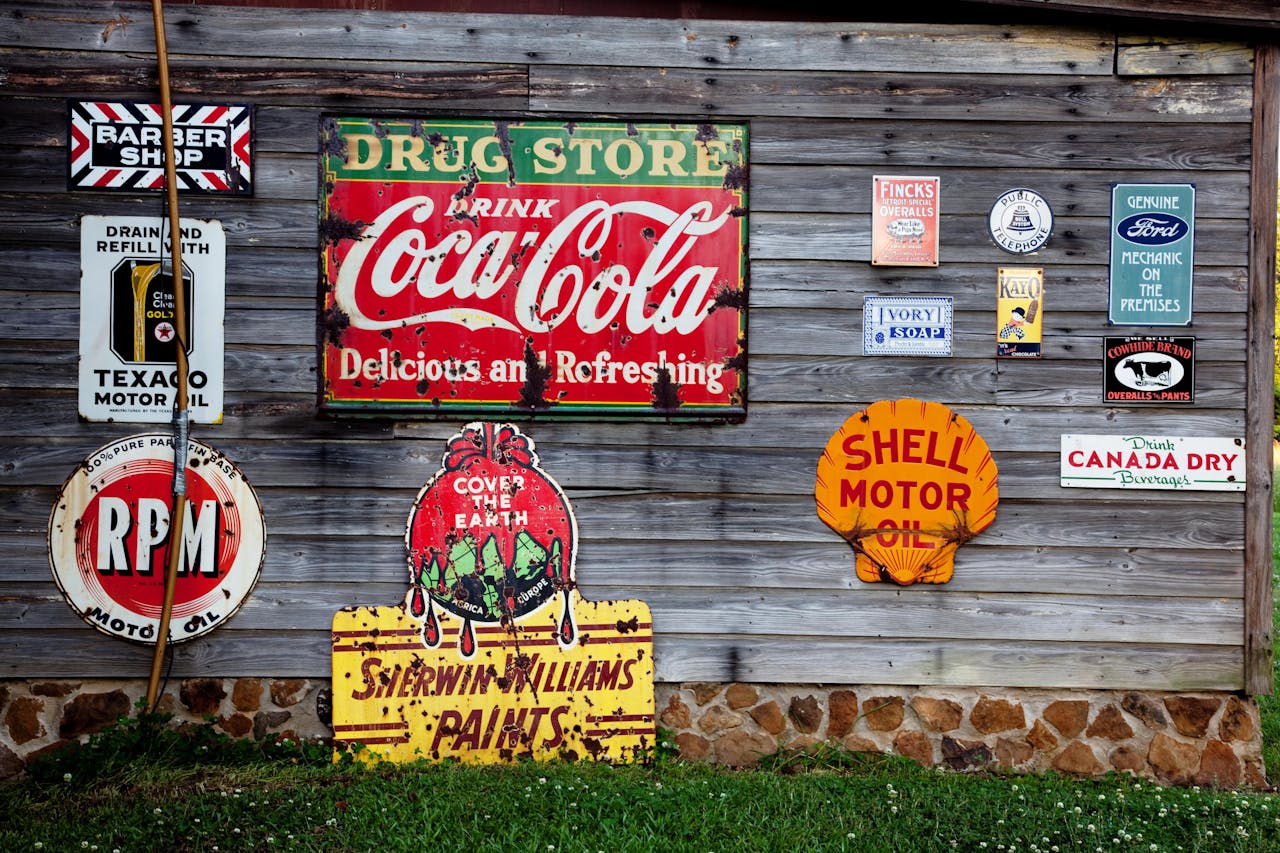 Home Collection of vintage advertising signs on rustic wooden wall showcasing classic brands.