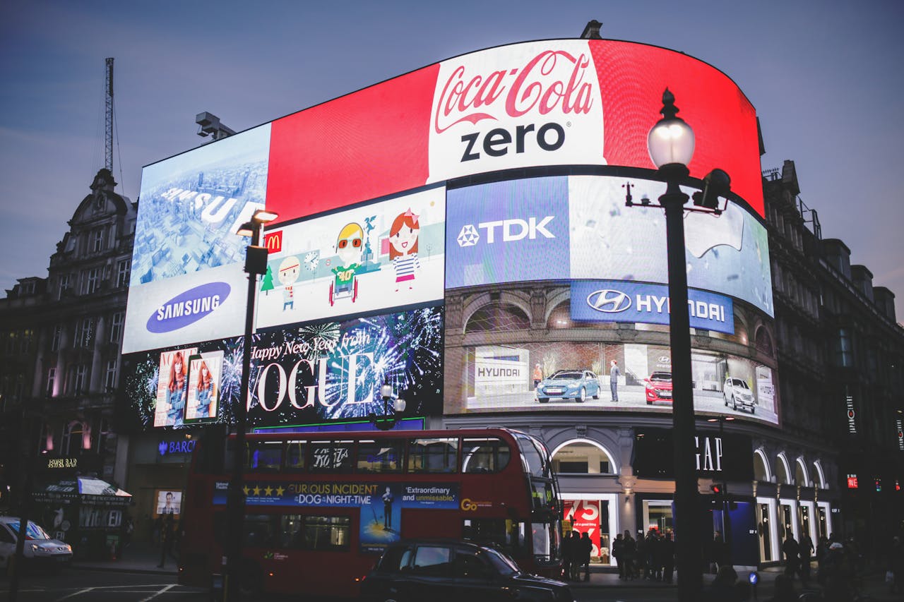 Home Night view of Piccadilly Circus in London with bright billboards and a red double-decker bus.